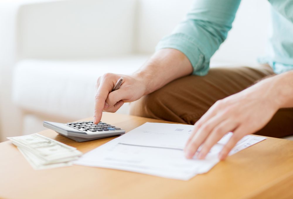 A man holding a pen, paper, and calculator