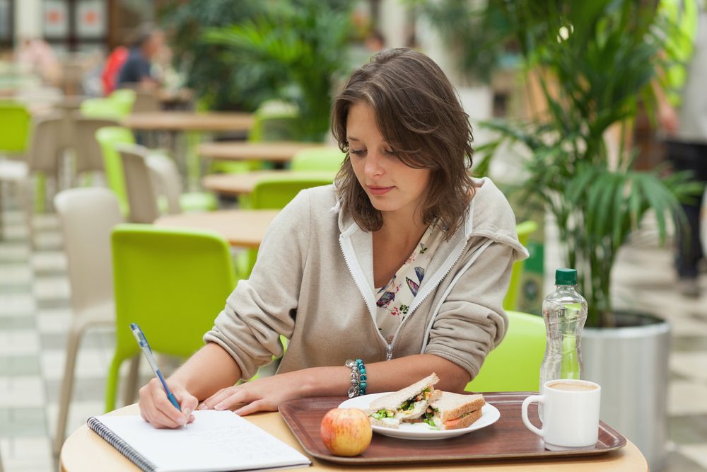 A young woman writing over her meal at a cafe