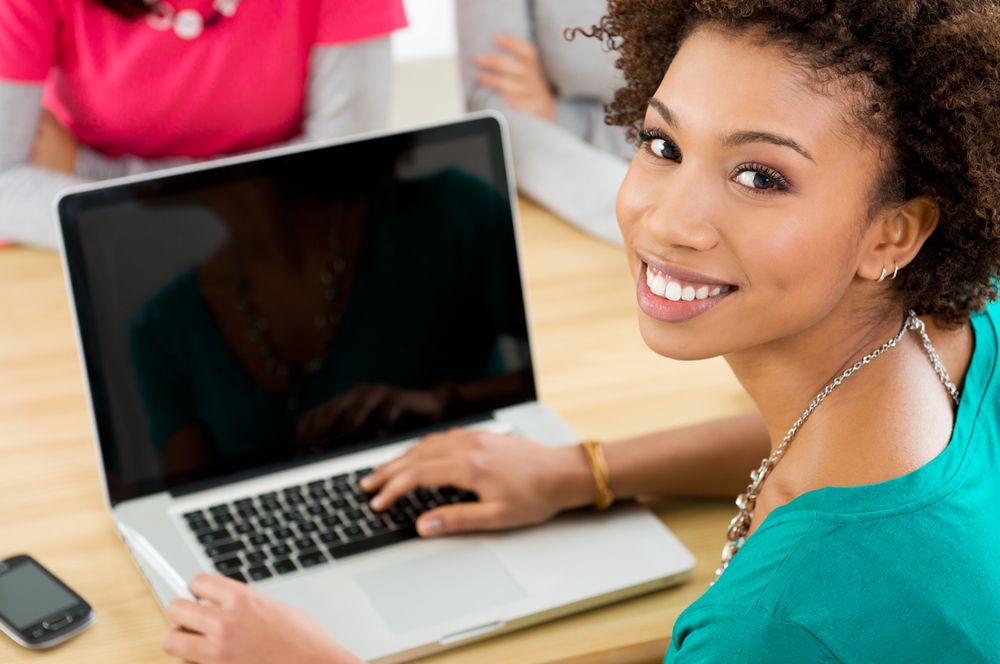 A young woman smiling and with a laptop