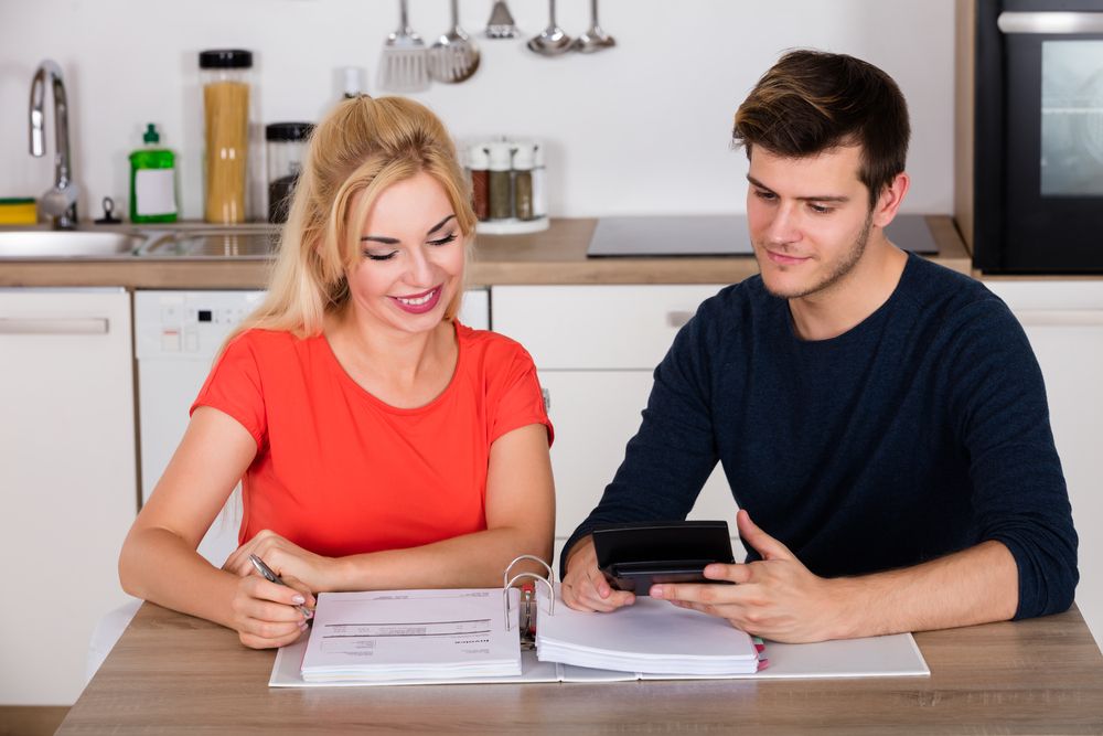 A couple making calculations using a calculator and binder