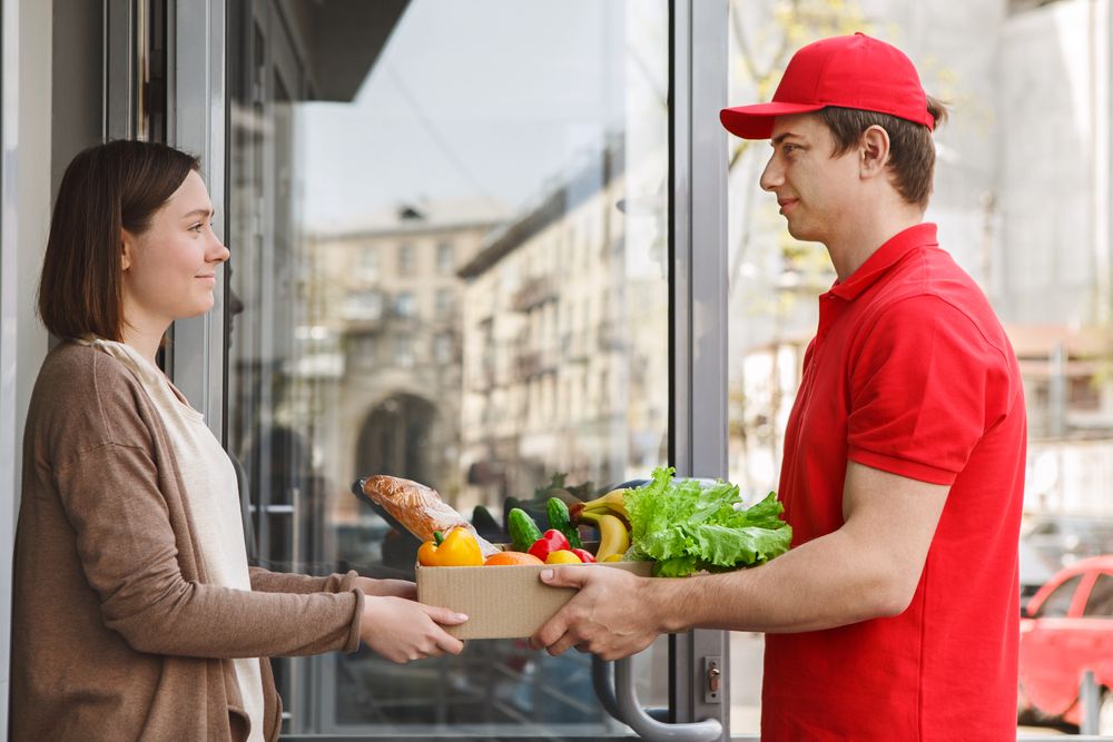 A woman taking groceries from a delivery man