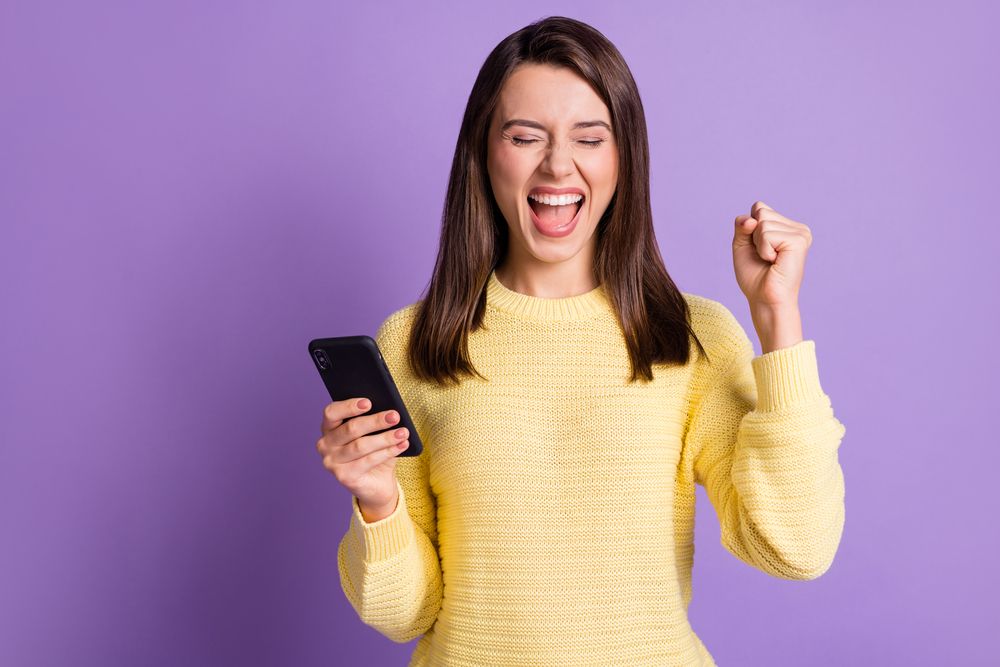A woman making a fist and holding a phone