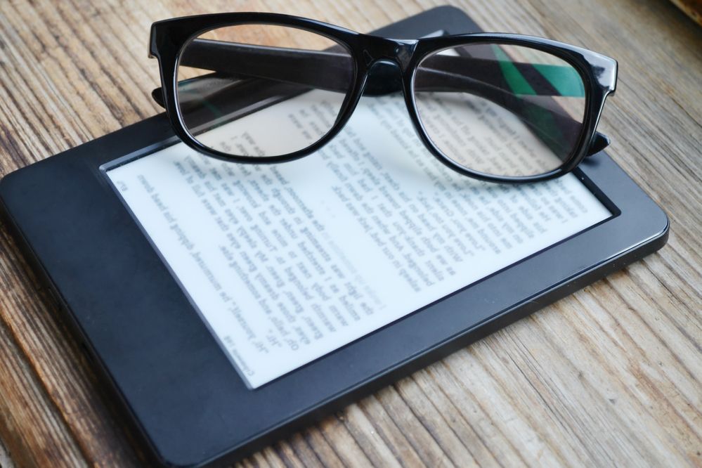 A pair of reading glasses sitting on a Kindle