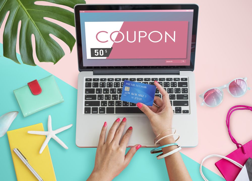 A laptop and credit card amid a summer concept flatlay