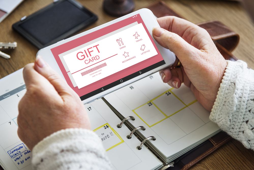 A woman's hands holding a mobile phone with gift card on screen