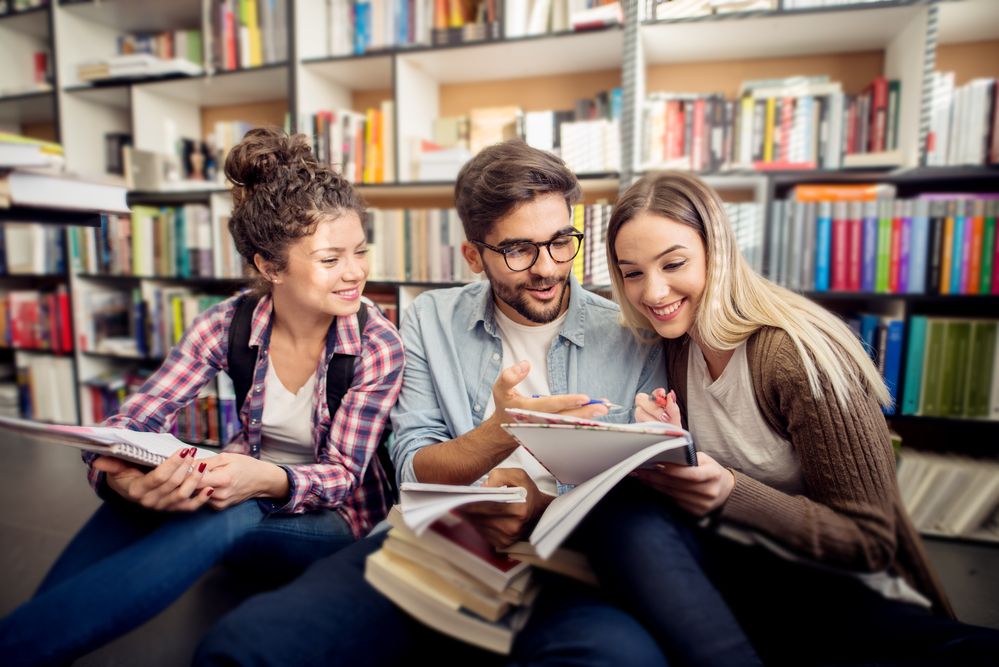 Two young women and a man in the library