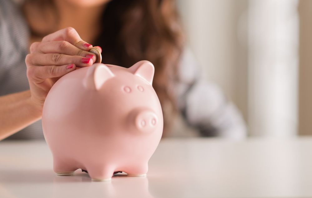 A woman putting a coin in a piggy bank