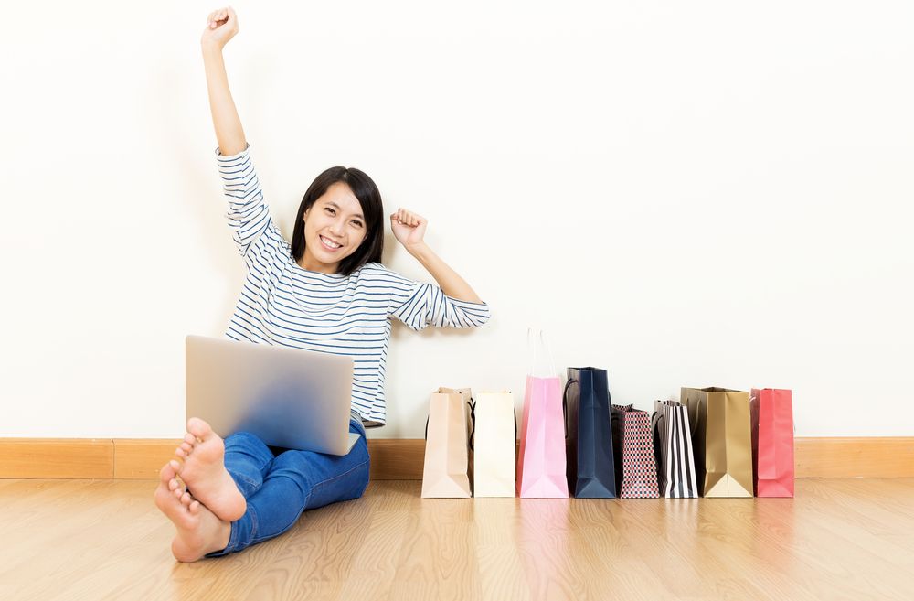 A woman sitting with a laptop and shopping bags