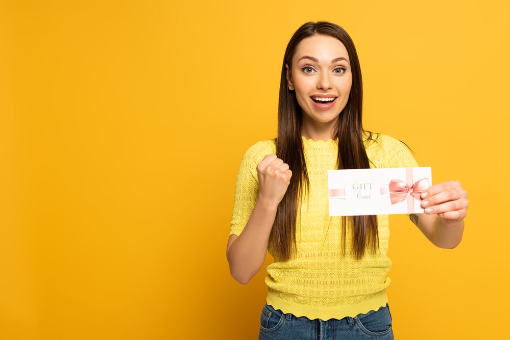 A woman making a fist and holding a physical gift card