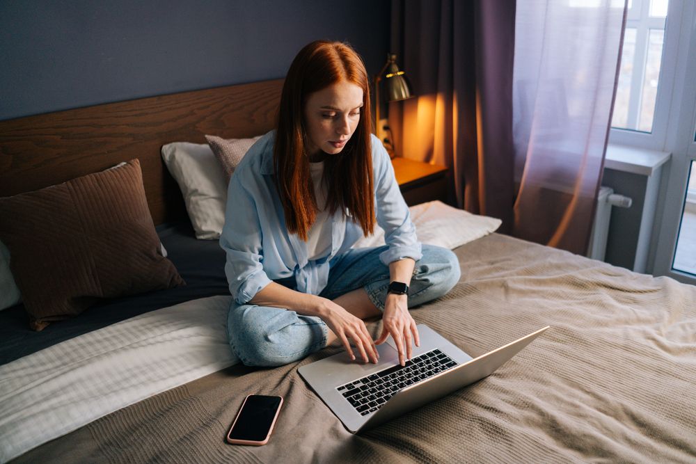 A woman using a laptop in bed