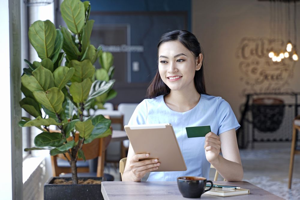 A woman holding a tablet and a card in a cafe