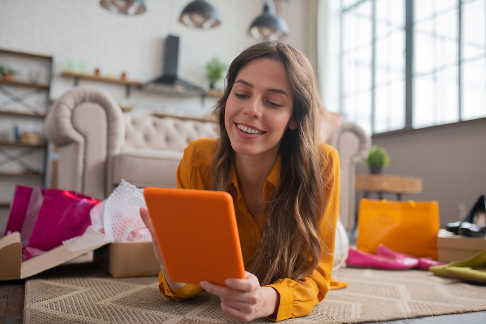 A woman on a tablet surrounded by shopping bags