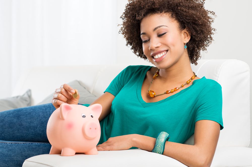 A woman putting a coin to a piggy bank