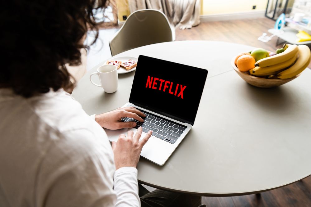A woman using a laptop with Netflix flashed on screen