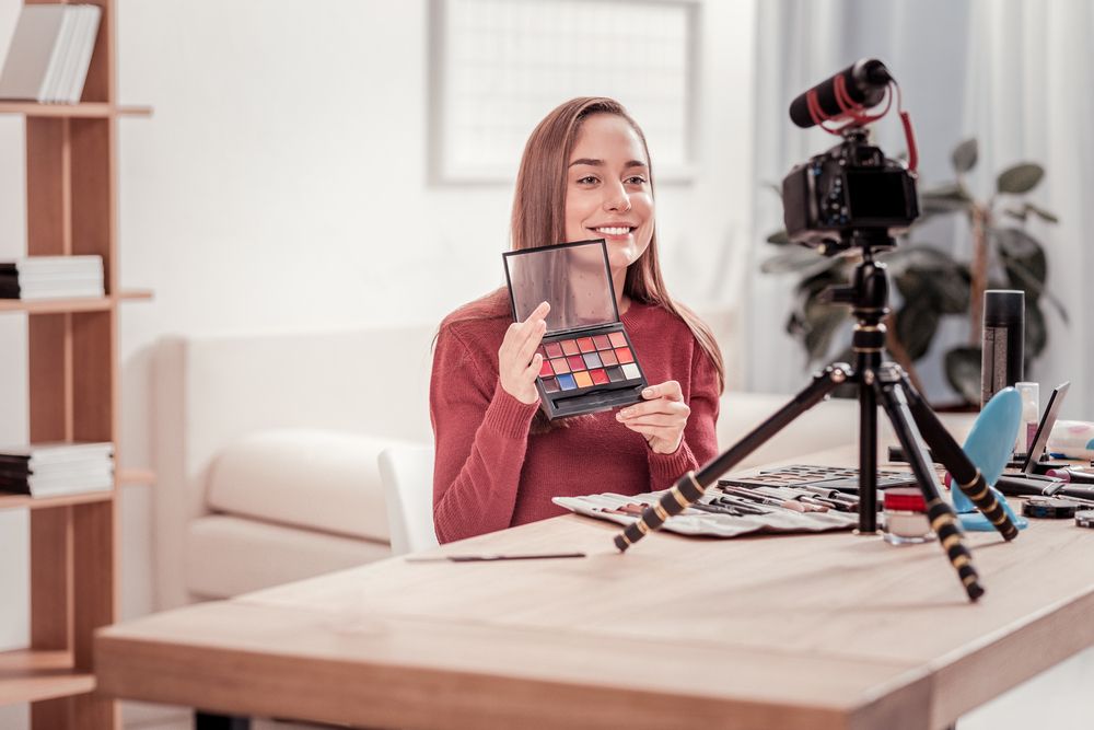 A woman holding cosmetics filming a video