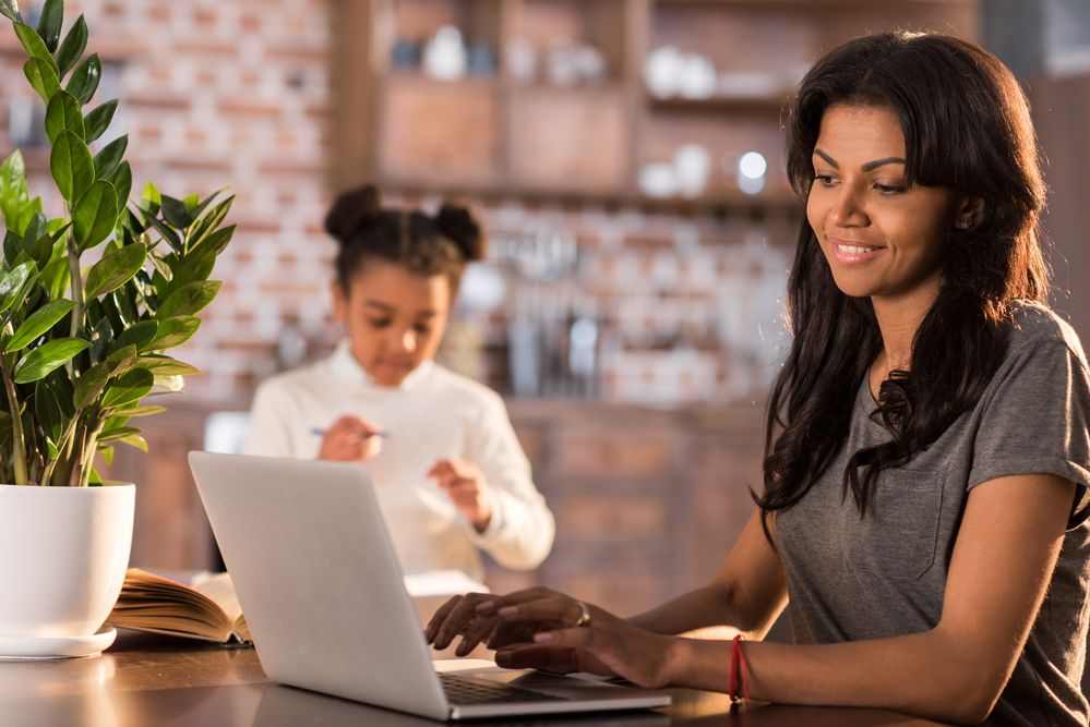 A woman, on her laptop, with a girl