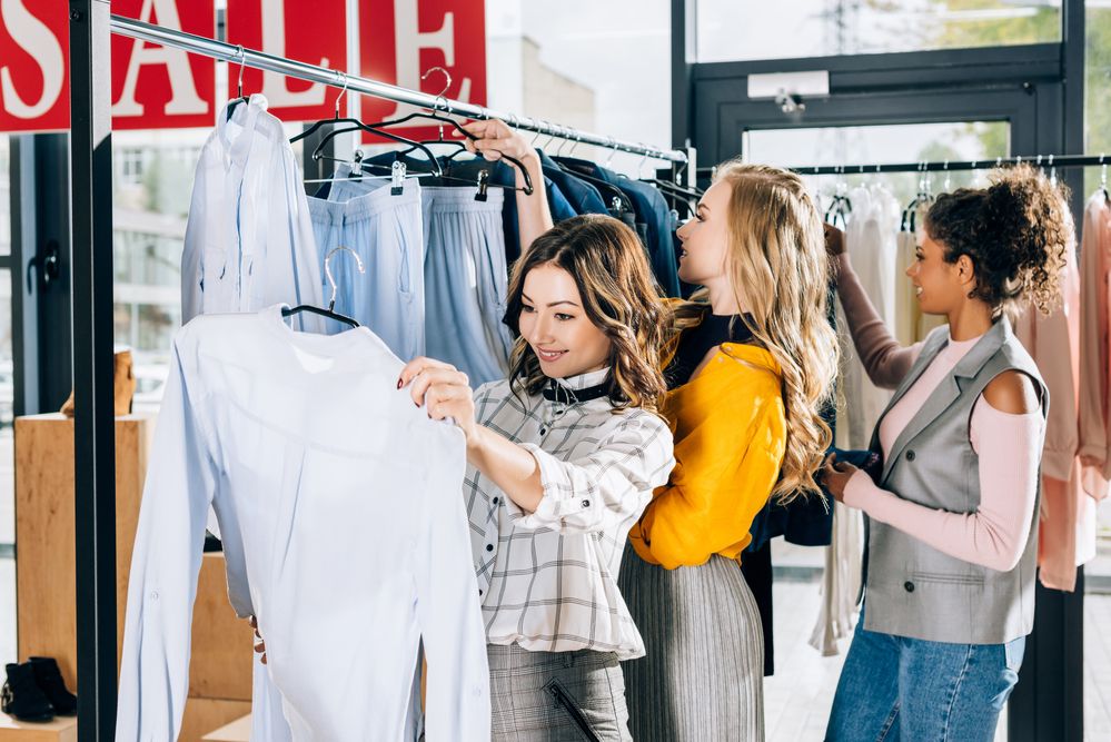 Three women shopping for clothes on sale