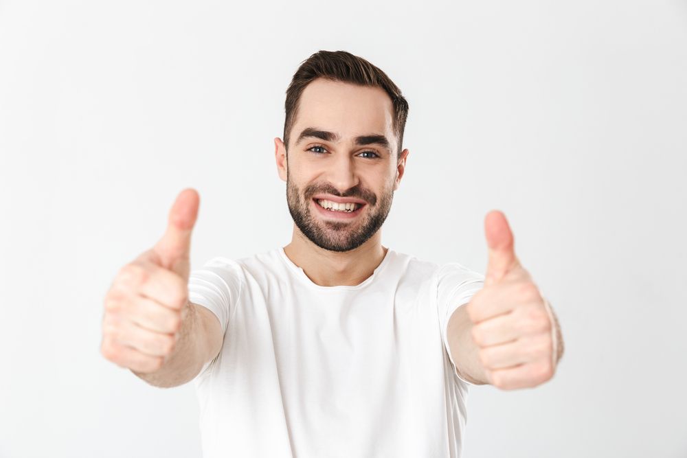 A young man giving a smile and two thumbs up