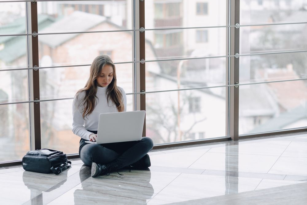 A young woman using a laptop inside an airport