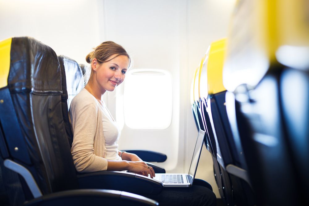 A young woman using a laptop inside an airplane