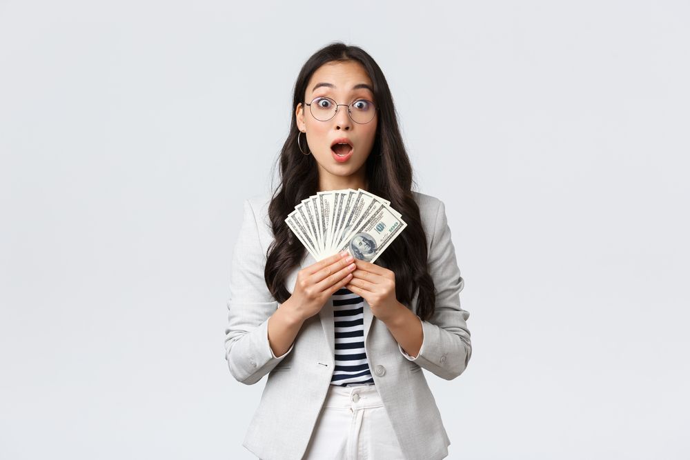 A young woman holding multiple dollar bills